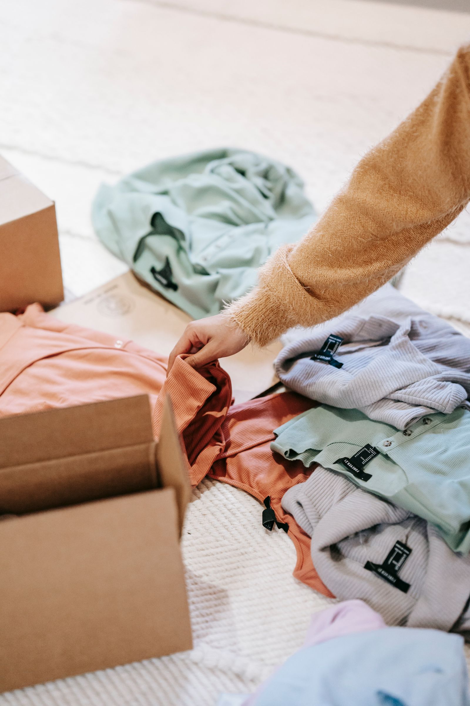 Turning an outgrown wardrobe into funding for the next one Woman packing folded clothes into a cardboard box to sell online
